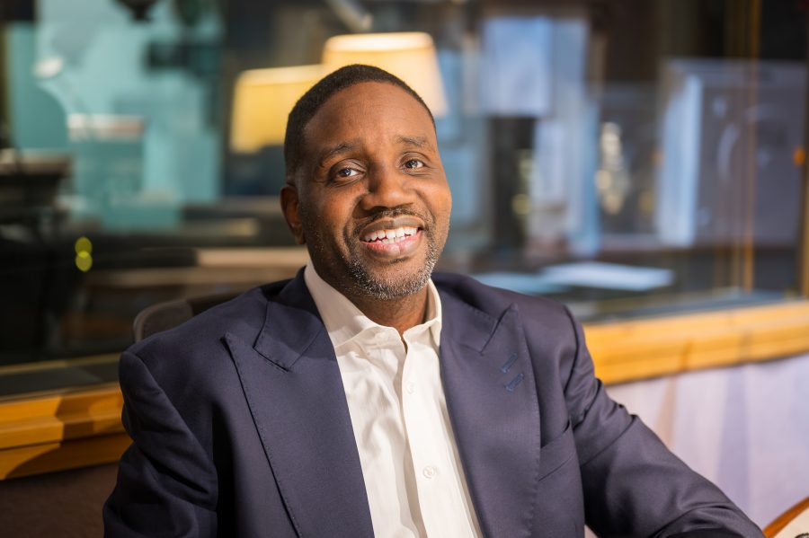 Detroit Pastor Solomon Kinloch Jr. smiling and sitting in the WDET studios in a blue suit.